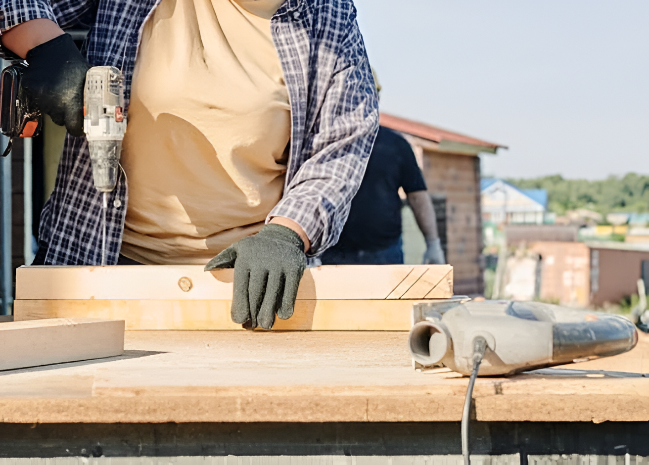 Un hombre usando un taladro sobre una mesa de madera.